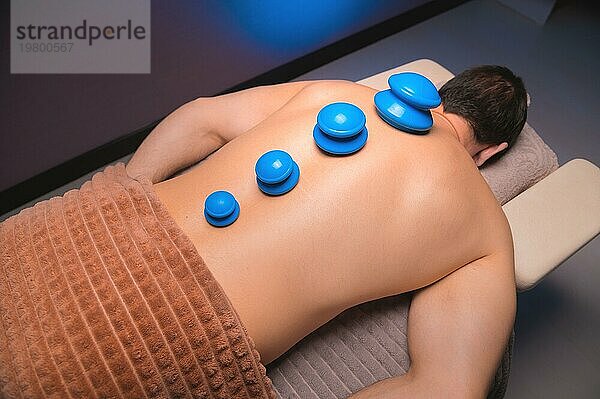 Vakuum Gummisauger für Schröpftherapie auf dem Rücken eines nackten Mannes. Massage im Spa  medizinische Behandlung für den Rücken. Revitalisierende und entspannende Massage  Fitnessbehandlungen