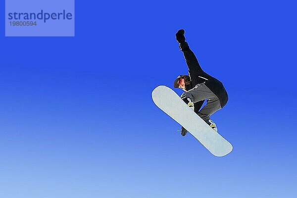 Snowboarder macht einen Grapple Jump Trick gegen den blaün Himmel. Blau Gradient Hintergrund isoliert Sportler im Flug