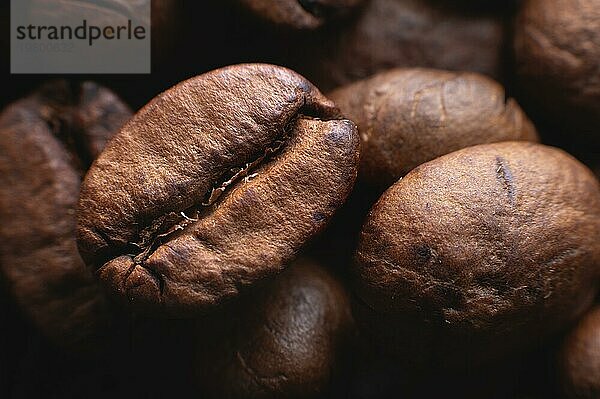 Close up extreme Makro Gruppe von gerösteten braunen oder schwarzen Kaffeebohnen Hintergrund in geringer Schärfentiefe. Betörendes Kaffeearoma