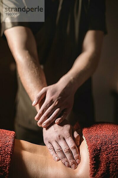 Kosmetologie und Physiotherapie. Professionelle Massage auf den unteren Rücken einer Frau wird von einem Masseur Mann gemacht. Konzept der manul Therapie und Massage Spabehandlungen