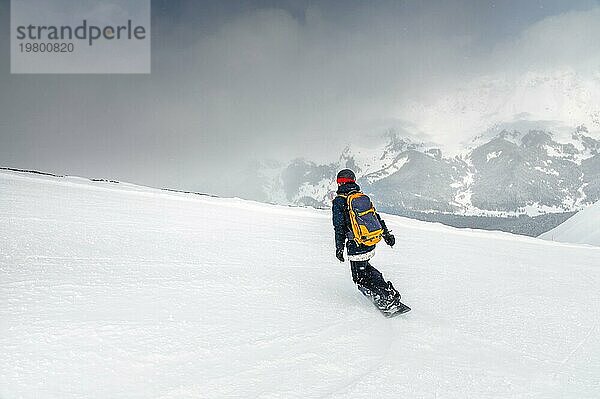 Junge Sportlerin Snowboarder Fahrt auf einem verschneiten Hang vor dem Hintergrund der Berge an einem Wintertag in einem Skigebiet