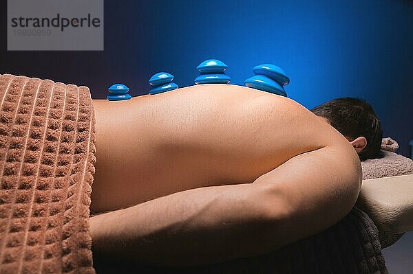 Vakuum Gummisauger für Schröpftherapie auf dem Rücken eines nackten Mannes. Massage im Spa  medizinische Behandlung für den Rücken. Revitalisierende und entspannende Massage  Fitnessbehandlungen