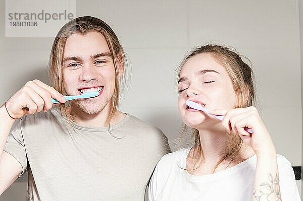 Ein junges Paar langhaariger Mellils putzt sich morgens im Badezimmer die Zähne. Ein gesundes Lächeln und Zahn und Mundpflege