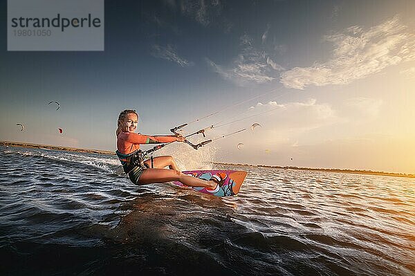 Wassersport. Das Mädchen ist in Kitesurfen mit einem Drachen in den Himmel an Bord in das blaue Meer beschäftigt  Reiten die Wellen mit Wasser spritzt. Freizeitaktivitäten  Wassersport  Aktivitäten  Hobbys und Unterhaltung im Sommer. kiteboarding