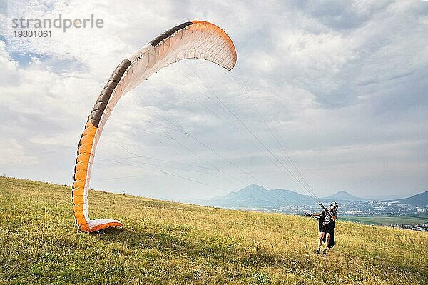 Der Gleitschirmflieger öffnet seinen Fallschirm  bevor er von einem Berg im Nordkaukasus abhebt. Füllen des Fallschirmflügels mit Luft vor dem Absprung