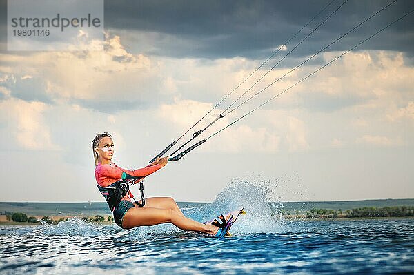 Eine junge Kitesurferin reitet auf den Wellen und zeigt einen Trick. Wassersport. Kitesurfen