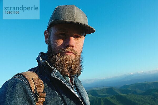 Porträt eines bärtigen stilvollen Reisenden mit einer Mütze vor blauem Himmel. Zeit zu reisen Konzept