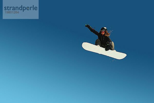 Snowboarder Mädchen macht einen Trick im Springen mit einem Greifer gegen den blaün Himmel. Blau Gradient Hintergrund isoliert Sportler im Flug