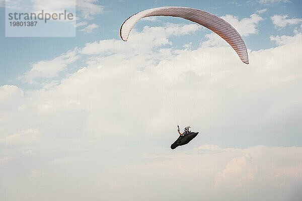 Alleine Gleitschirm fliegen in den blaün Himmel vor dem Hintergrund der Wolken. Paragliding in den Himmel an einem sonnigen Tag