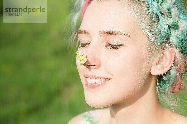 Gelber Schmetterling auf der Nase sitzend Niedliches junges Mädchen in der Natur. Harmonie und Freude an der Natur