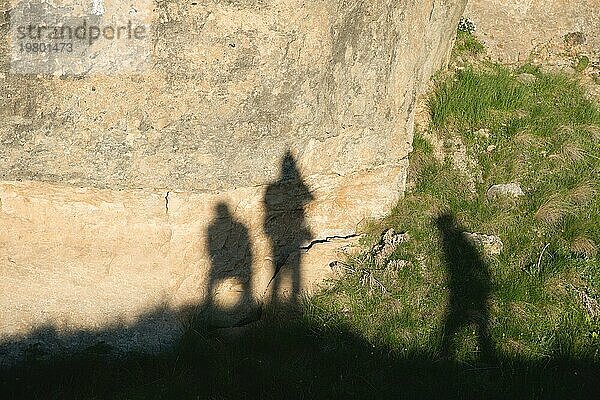 Schatten von drei Reisenden Freunde auf gelben Felsen neben grünem Gras