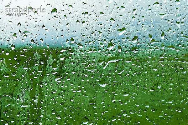 Natürlicher Hintergrund Tropfen auf beiden Seiten des Glases vom Regen und vom Beschlagen abstrakte Ansicht  Regentropfen gegen das blaue Glas und die verschwommene Landschaft des Farbverlaufs von Blau und Grün