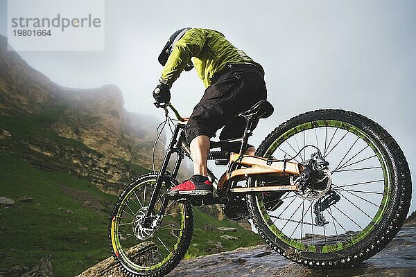 Extreme Mountainbike Sportler Mann mit Helm fahren im Freien vor einem Hintergrund von Felsen. Lebensstil. Trial