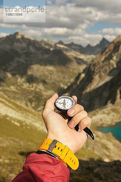 Ein Mann hält einen Taschenmagnetkompass zur Navigation vor dem Hintergrund eines felsigen Abhangs und eines Berges in der Hand. Das Konzept  einen Weg zu finden. Freiheit gewinnen. Freiheit der Wahl