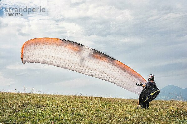 Der Gleitschirmflieger öffnet seinen Fallschirm  bevor er von einem Berg im Nordkaukasus abhebt. Füllen des Fallschirmflügels mit Luft vor dem Absprung