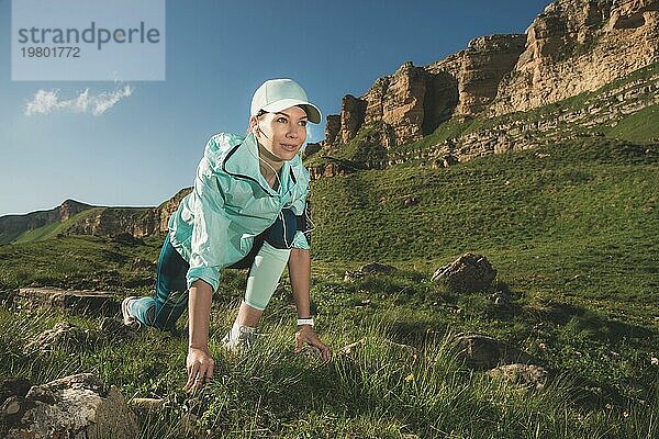 Sportliche Frau war bereit  am Fuße der Felsen zu laufen. Fitness Läufer in der fertigen Startlinie schafft eine Outdoor Sommer Sprint Herausforderung