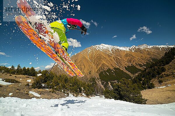 Nahaufnahme einer Skifahrerin  die ein Schneesprungbrett in den Bergen im Vorfrühling abfährt. Raum kopieren