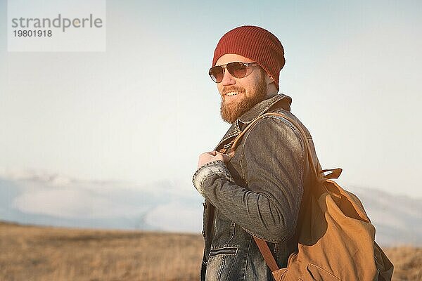 Hipster junger Mann mit Bart und Schnurrbart und Sonnenbrille posiert vor dem Hintergrund der Berge