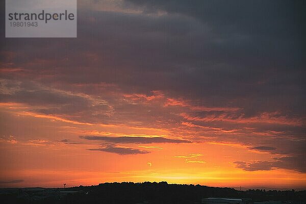 Abendhimmel nach Sonnenuntergang mit roten Wolken und die Silhouette des privaten Sektor einer kleinen Stadt