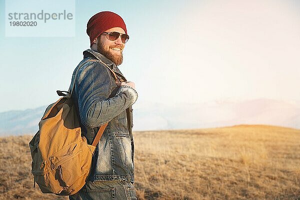 Hipster junger Mann mit Bart und Schnurrbart und Sonnenbrille posiert vor dem Hintergrund der Berge