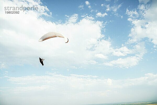 Alleine Gleitschirm fliegen in den blaün Himmel vor dem Hintergrund der Wolken. Paragliding in den Himmel an einem sonnigen Tag