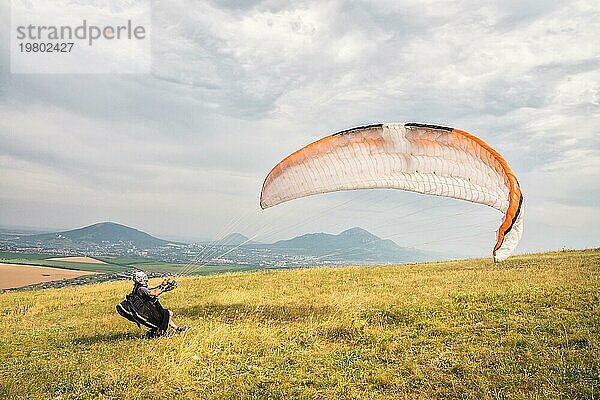 Der Gleitschirmflieger öffnet seinen Fallschirm  bevor er von einem Berg im Nordkaukasus abhebt. Füllen des Fallschirmflügels mit Luft vor dem Absprung