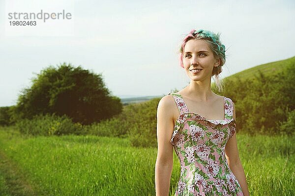 Porträt eines jungen  glücklich lächelnden Mädchens in einem Baumwollkleid mit einem Strauß Wildblumen