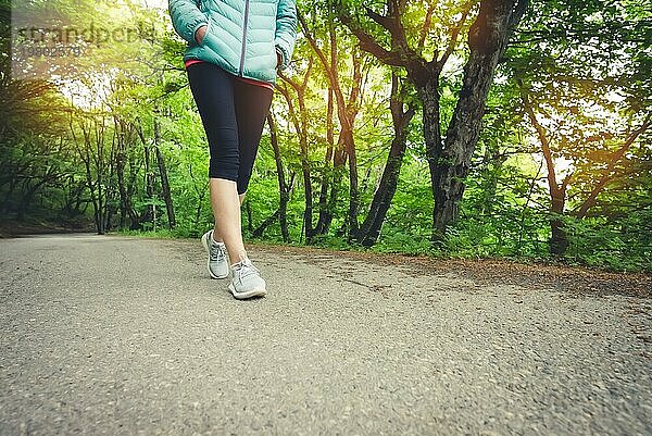 Nahaufnahme des Fußes eines sportlichen Mädchens in Leggings und Turnschuhen vor dem Joggen im Wald. Das Konzept des Outdoor Sports