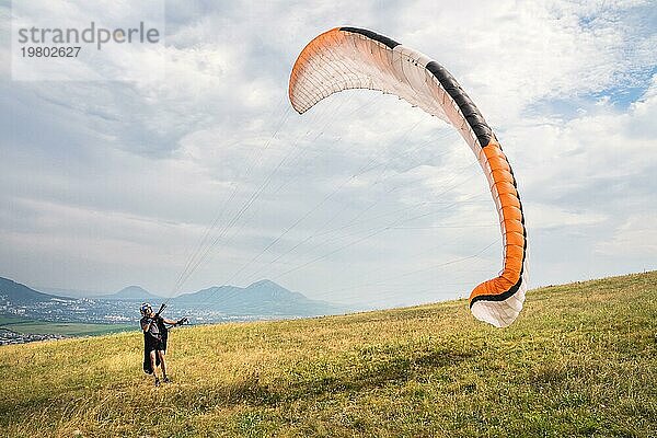 Der Gleitschirmflieger öffnet seinen Fallschirm  bevor er von einem Berg im Nordkaukasus abhebt. Füllen des Fallschirmflügels mit Luft vor dem Absprung