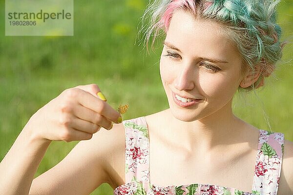 Porträt einer schönen Frau  die einen Schmetterling auf ihrer Hand im Garten hält. Porträt der Schönheit. Einheit mit der Natur. Ökologie Konzept
