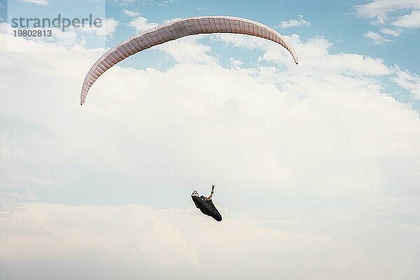 Alleine Gleitschirm fliegen in den blaün Himmel vor dem Hintergrund der Wolken. Paragliding in den Himmel an einem sonnigen Tag