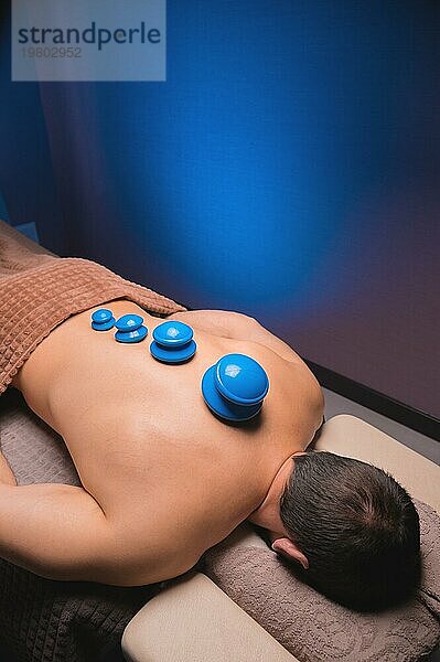 Vakuum Gummisauger für Schröpftherapie auf dem Rücken eines nackten Mannes. Massage im Spa  medizinische Behandlung für den Rücken. Revitalisierende und entspannende Massage  Fitnessbehandlungen