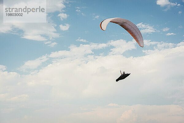 Alleine Gleitschirm fliegen in den blaün Himmel vor dem Hintergrund der Wolken. Paragliding in den Himmel an einem sonnigen Tag