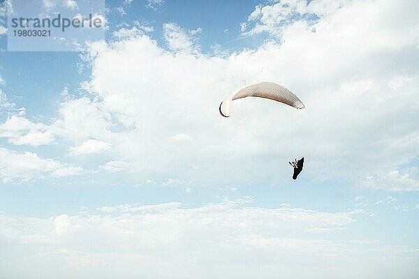 Alleine Gleitschirm fliegen in den blaün Himmel vor dem Hintergrund der Wolken. Paragliding in den Himmel an einem sonnigen Tag