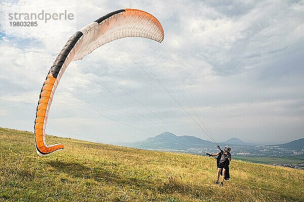 Der Gleitschirmflieger öffnet seinen Fallschirm  bevor er von einem Berg im Nordkaukasus abhebt. Füllen des Fallschirmflügels mit Luft vor dem Absprung