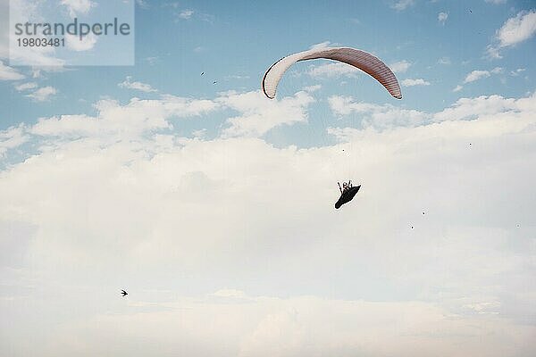 Alleine Gleitschirm fliegen in den blaün Himmel vor dem Hintergrund der Wolken. Paragliding in den Himmel an einem sonnigen Tag