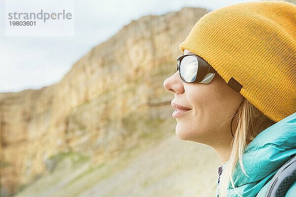 Close up Porträt eines Mädchens Reisende in einem Hut und Klettern Sonnenbrille. Glückliches Mädchen auf dem Hintergrund von Felsen