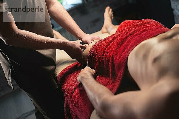 Männliche professionelle Sportmassage der Hüfte und des Knies in einem dunklen Massageraum. hochwertige Massagedienstleistungen. Kopierraum