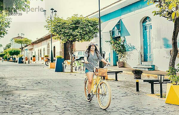 Schönes und glückliches Mädchen beim Fahrradfahren auf der Straße von La Calzada  Granada  Nicaragua. Tourist Frau fährt ein Fahrrad auf den Straßen von Granada