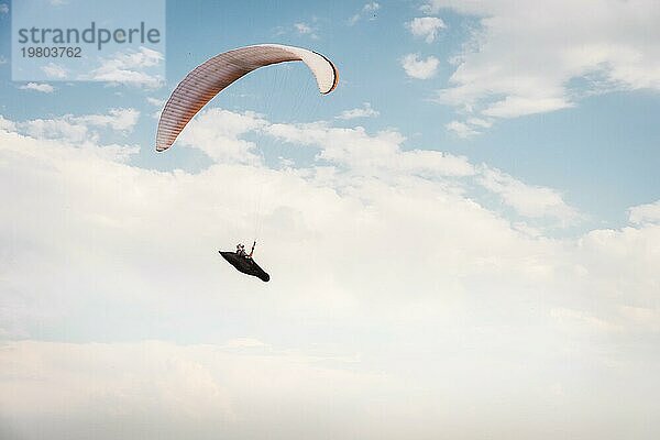 Alleine Gleitschirm fliegen in den blaün Himmel vor dem Hintergrund der Wolken. Paragliding in den Himmel an einem sonnigen Tag