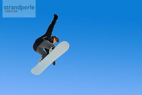 Snowboarder Mädchen macht einen Trick im Springen mit einem Greifer gegen den blaün Himmel. Blau Gradient Hintergrund isoliert Sportler im Flug