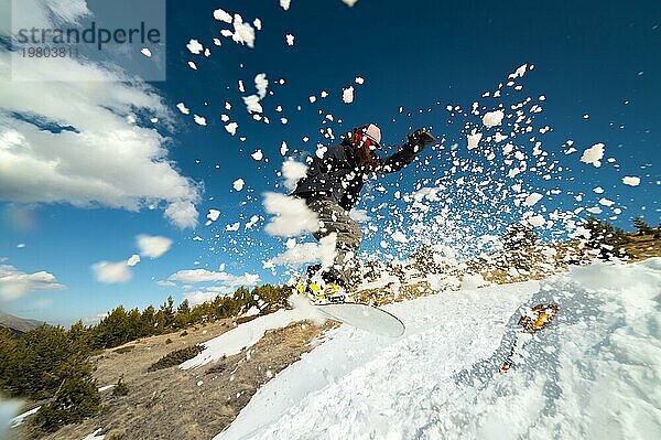 Stylish junges Mädchen Snowboarder macht den Trick beim Springen von einem Schnee Kicker gegen den blaün Himmel Wolken und Berge im Frühjahr. Das Konzept der Frühling Snowboarden in den Bergen und die Schließung der Winter Ski Saison