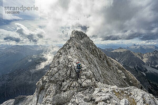 Bergsteigerin auf einem schmalen felsigen Berggrat  Watzmann Überschreitung zur Watzmann Mittelspitze  Ausblick auf Bergpanorama mit Steinernes Meer  Nationalpark Berchtesgaden  Berchtesgadener Alpen  Bayern  Deutschland  Europa