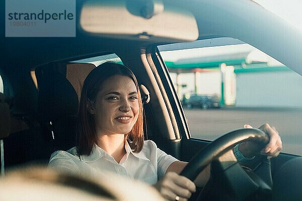 Junge schöne Mädchen Taxifahrer lächelnd hinter dem Lenkrad  freundliche Kommunikation mit den Passagieren