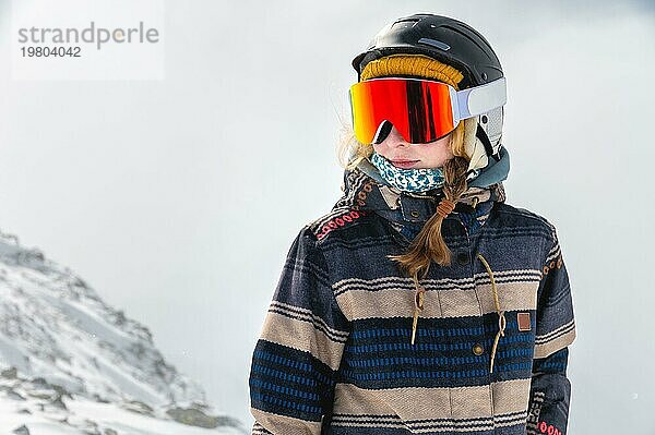 Porträt einer Sportlerin mit Helm und Maske  die wegschaut und den frostigen Tag genießt ein perfekter Tag zum Snowboarden oder Skifahren