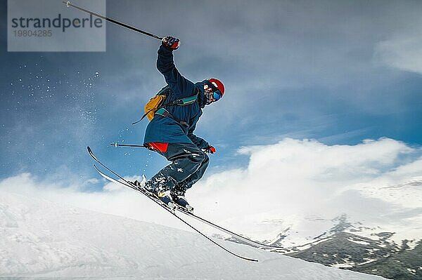 Männlicher Skifahrer  der vom Berg springt und eine Schneefahne erzeugt  Winter Extremsport  Skifahren