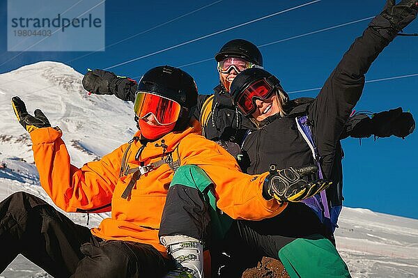 Lachende Freunde im Winterurlaub beim Skifahren in verschneiten Bergen  Blick in die Kamera. Eine Gesellschaft von Menschen genießt einen Winterurlaub in einem Skigebiet