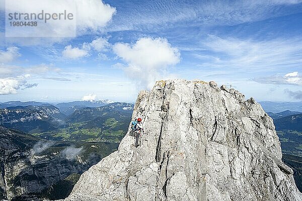 Bergsteigerin klettert in einem mit Stahlseil gesicherten Klettersteig  schmaler felsiger Berggrat  Watzmann Überschreitung zur Watzmann Mittelspitze  Nationalpark Berchtesgaden  Berchtesgadener Alpen  Bayern  Deutschland  Europa