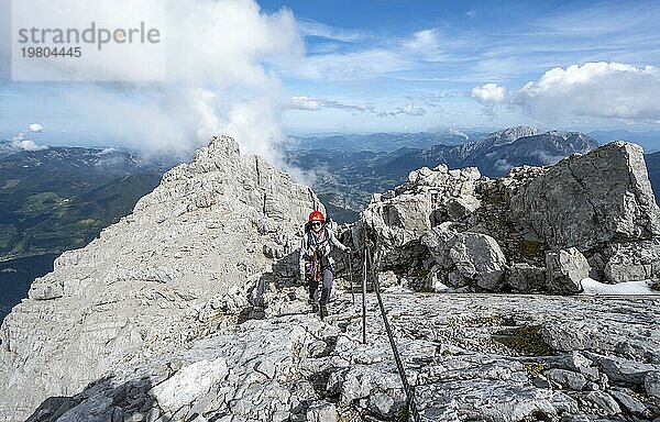 Bergsteigerin in einem mit Stahlseil gesicherten Klettersteig  schmaler felsiger Berggrat  Watzmann Überschreitung zur Watzmann Mittelspitze  Nationalpark Berchtesgaden  Berchtesgadener Alpen  Bayern  Deutschland  Europa