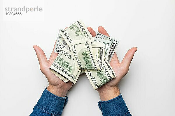 Männerhände halten ein Bündel gefaltetes Geld  Dollarscheine  eine Schuld zurückzahlen. Studioaufnahme  weißer Hintergrund